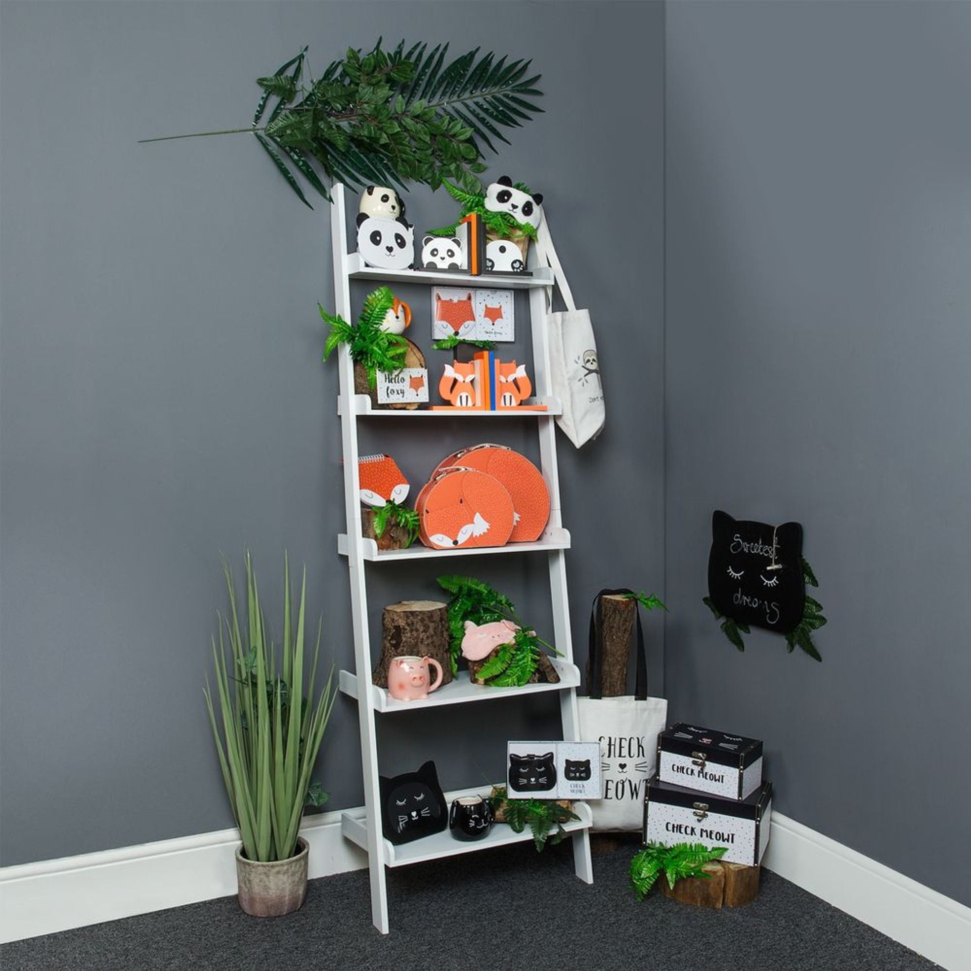 White ladder shelf against a gray wall with decorative items and plants.