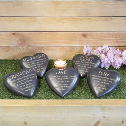 Heart-shaped memorial stones with engravings on a wooden surface with flowers