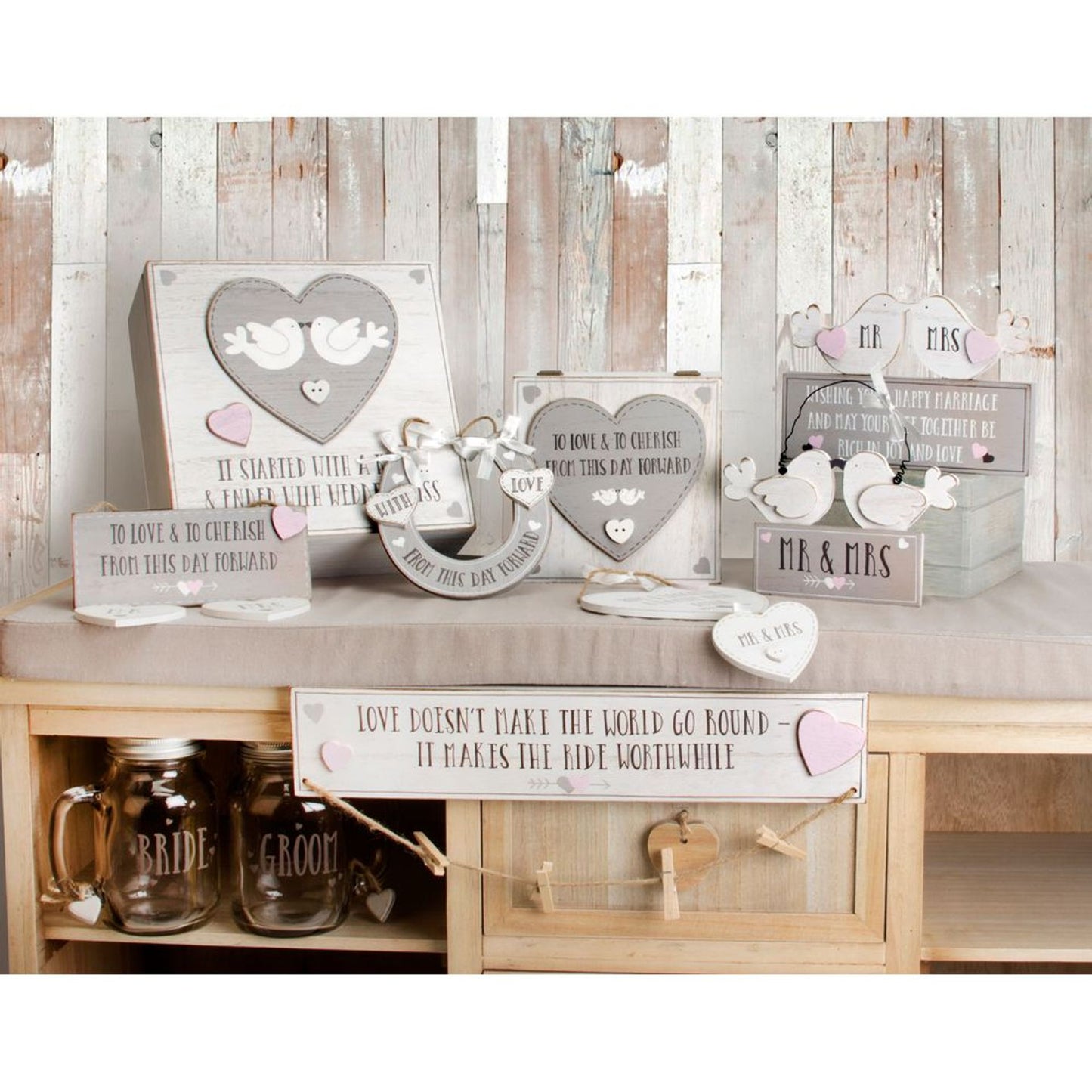 Decorative wedding signs and mugs on a wooden shelf against a rustic wooden wall.