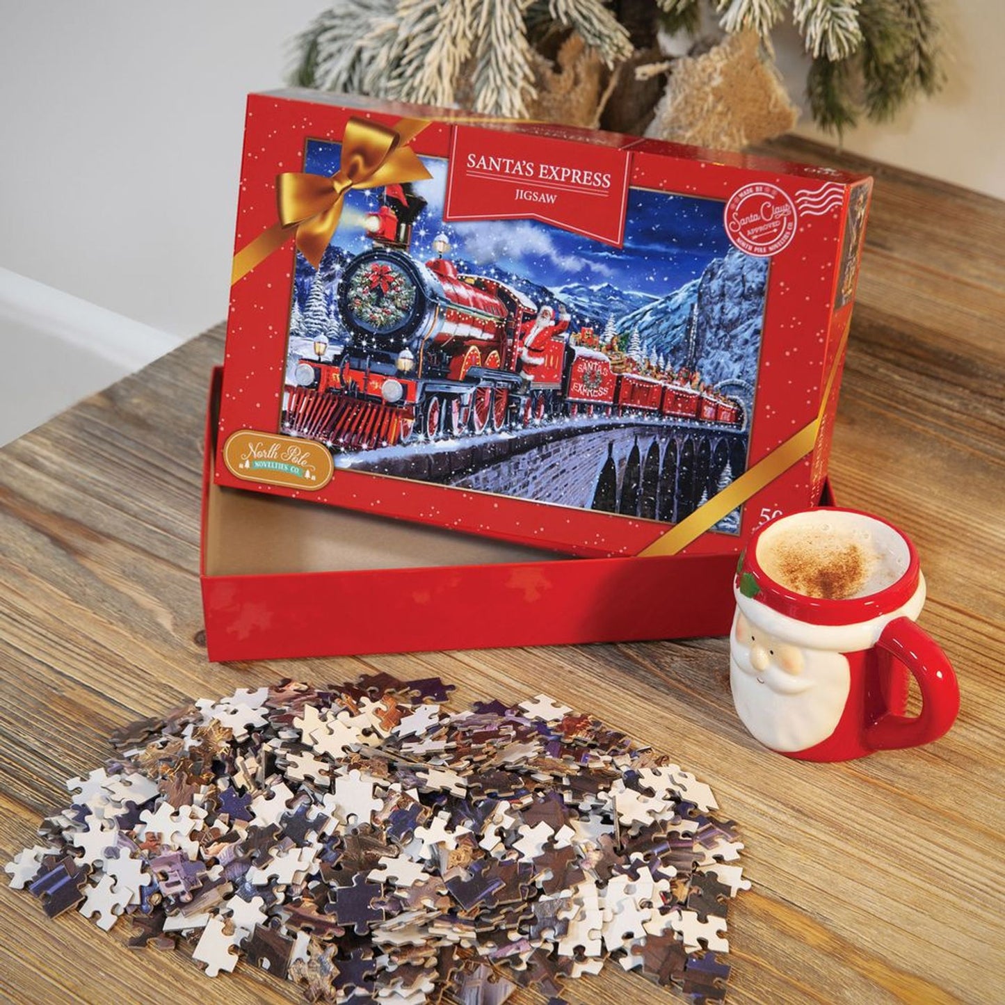Jigsaw puzzle set with a Santa's Express train box, puzzle pieces, and a mug on a wooden surface.