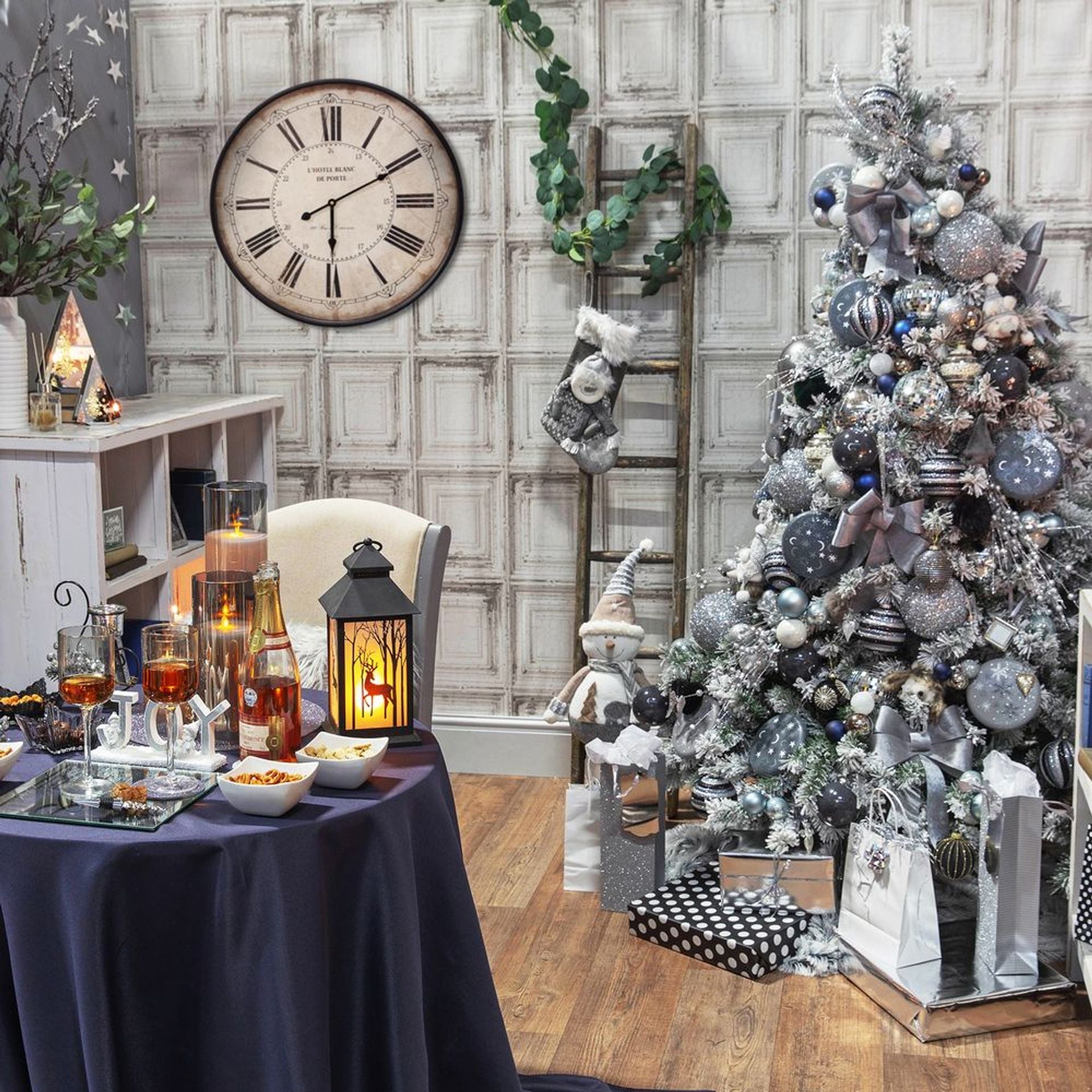 Decorated room with a Christmas tree, table with drinks, and wall clock.