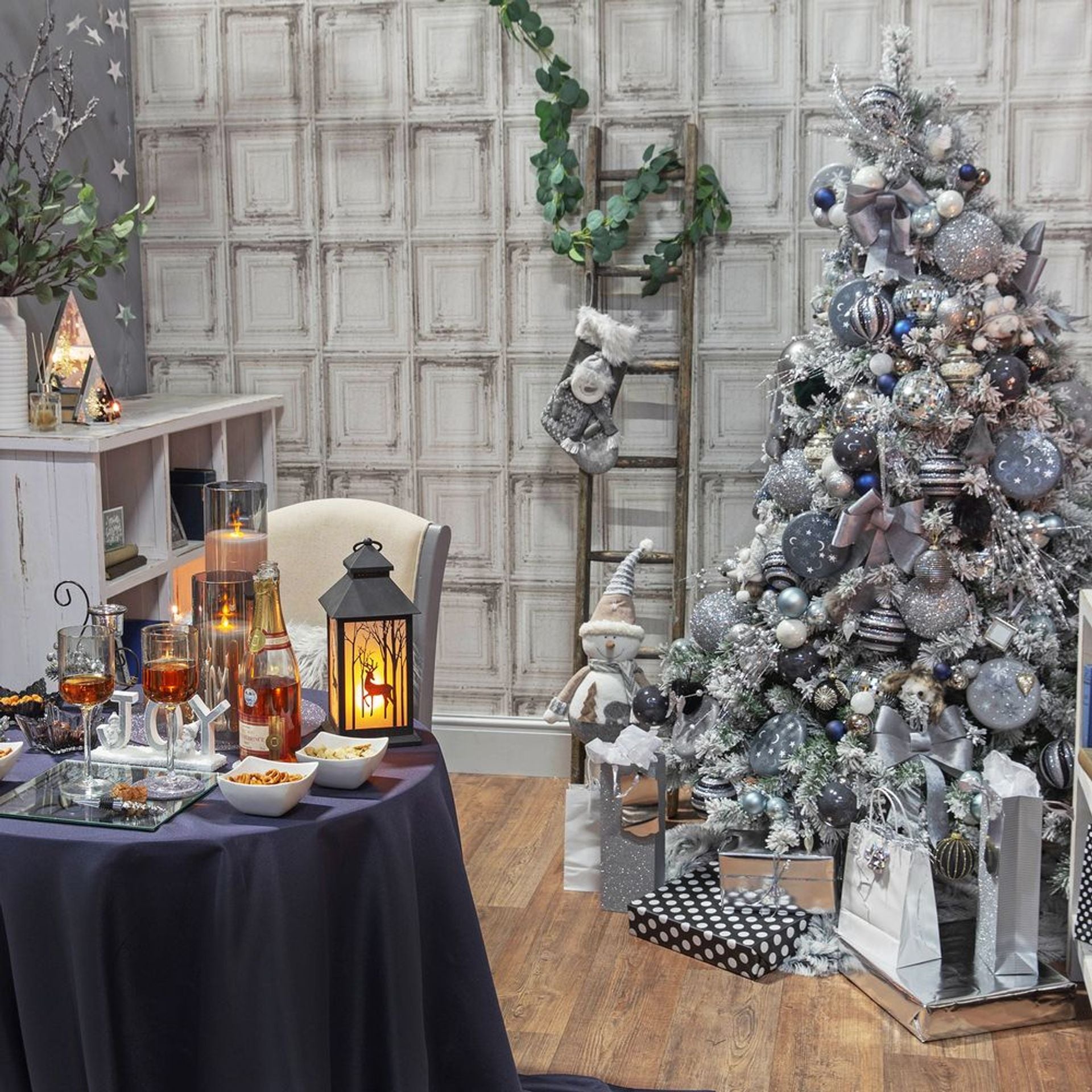 Decorated Christmas tree with a table set for a festive gathering in a room with a checkered wall.