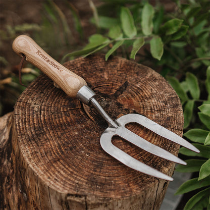 Gardening tool with wooden handle on a wooden log surrounded by greenery