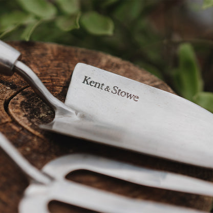 Fork with 'Kent & Stowe' branding on a wooden surface with greenery in the background