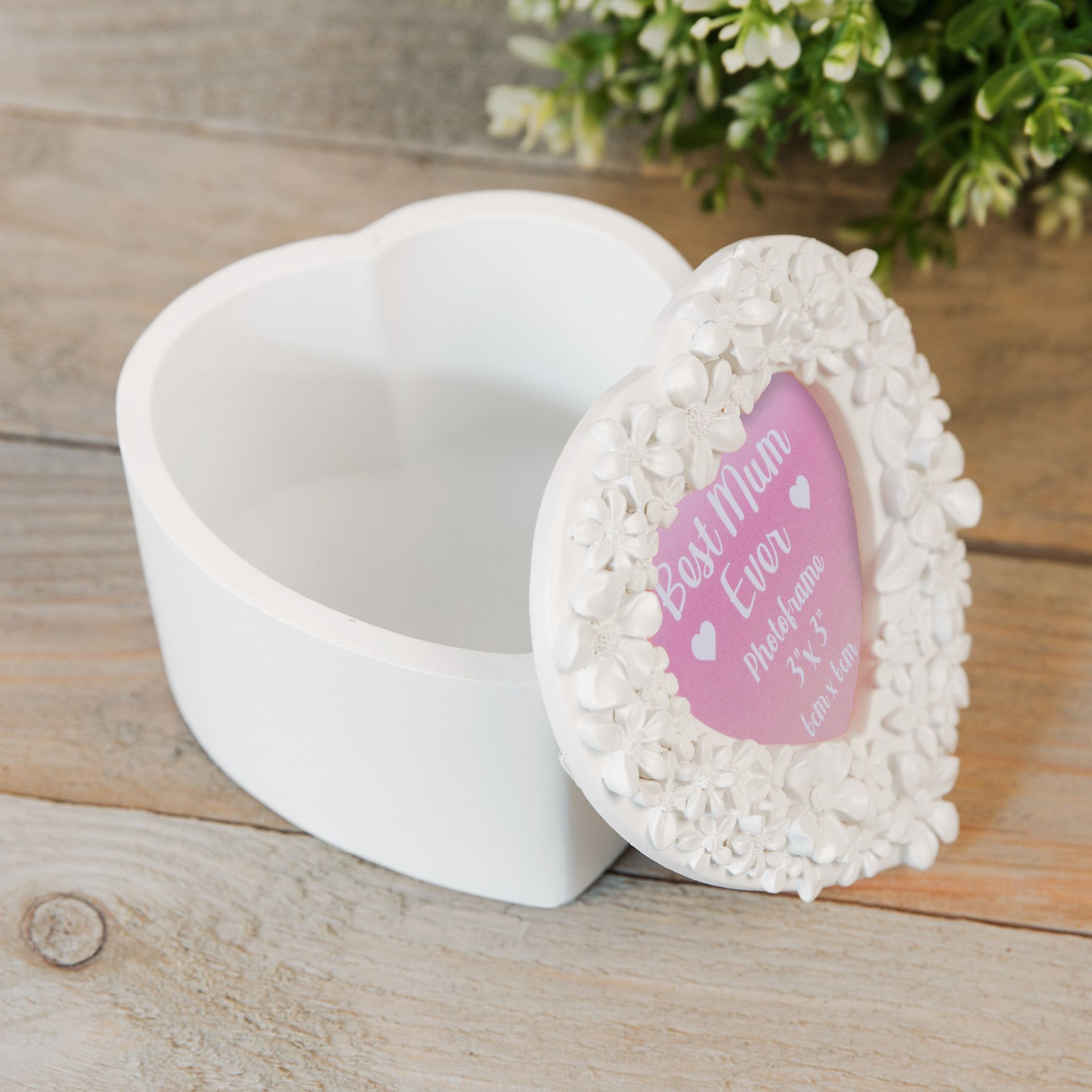 Heart-shaped photo frame with decorative border on a wooden surface
