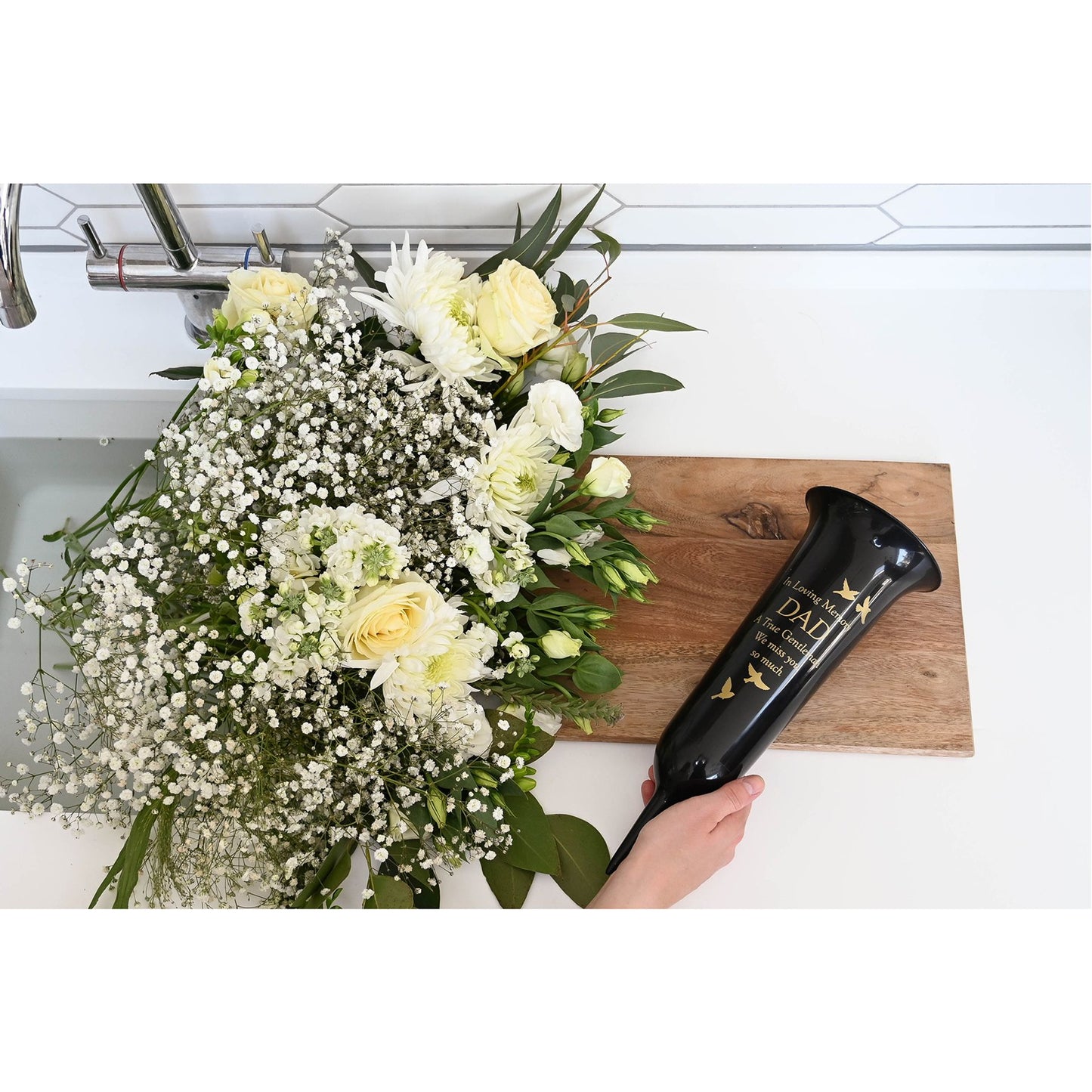 Bouquet of white flowers on a wooden cutting board with a hair dryer labeled 'Dali' nearby.