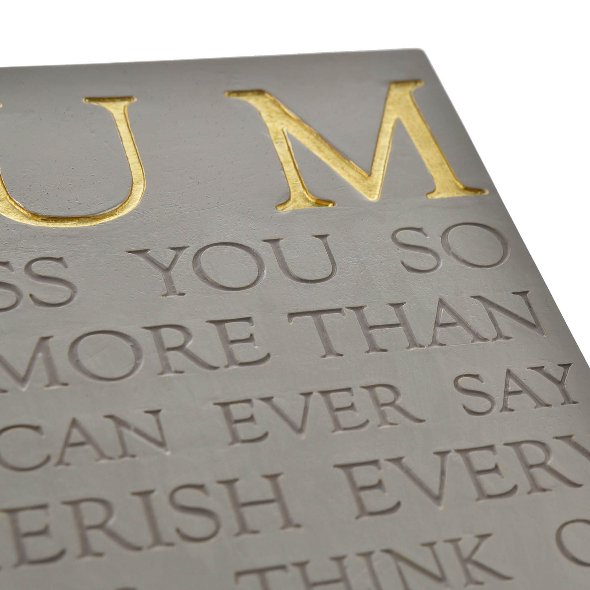 Embossed text on a metallic surface with gold and silver colors.