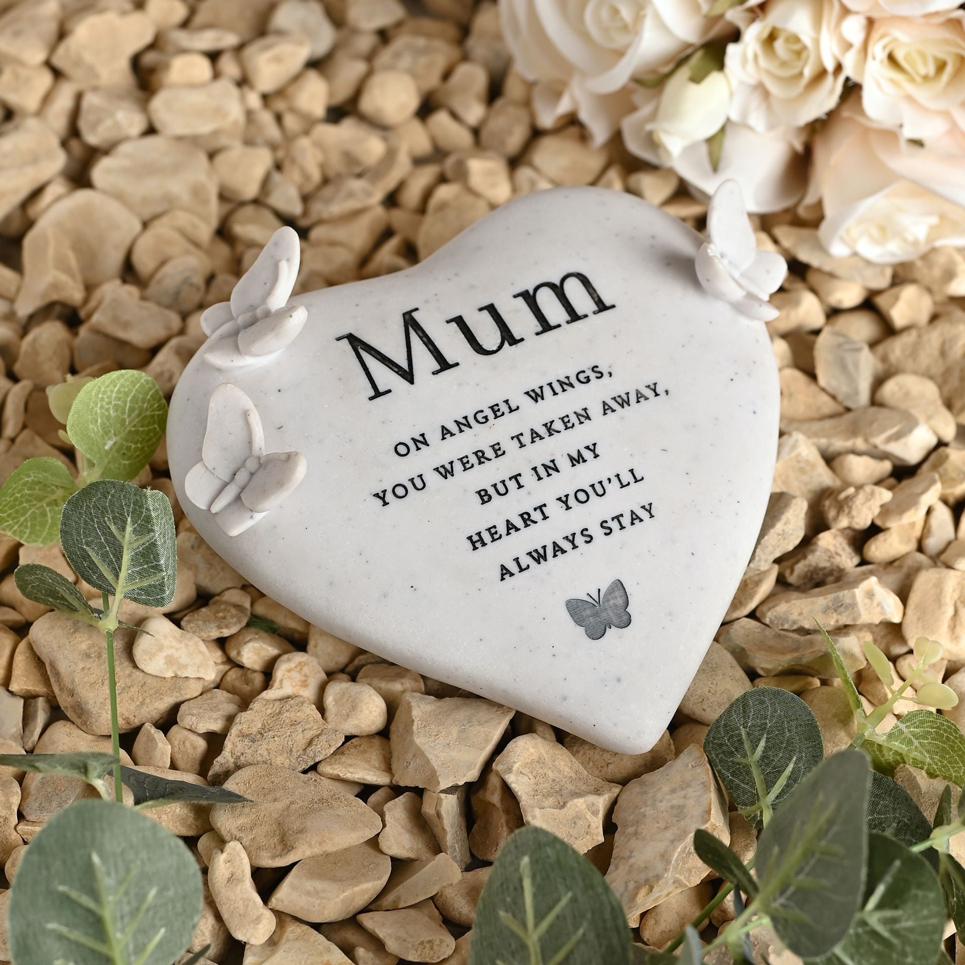Memorial stone with 'Mum' inscription on a bed of stones and flowers
