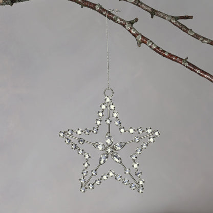 Decorative star hanging from a branch against a gray background