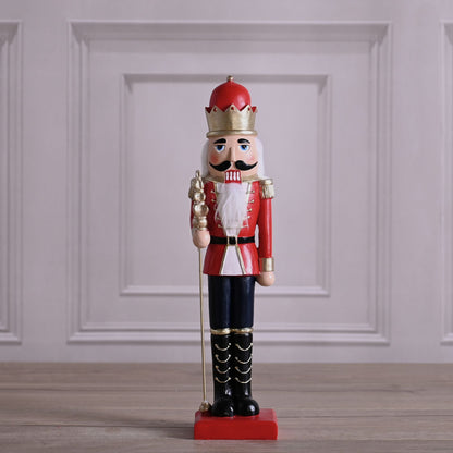 Decorative nutcracker figure with red outfit and crown on a wooden floor.