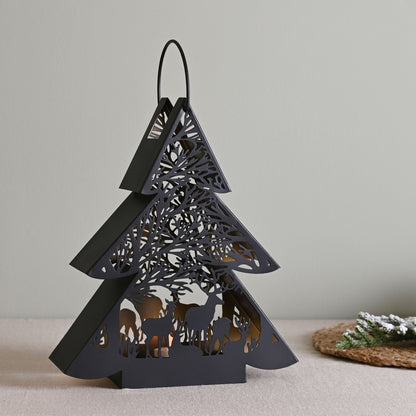 Black decorative lantern shaped like a Christmas tree with cut-out designs on a neutral background