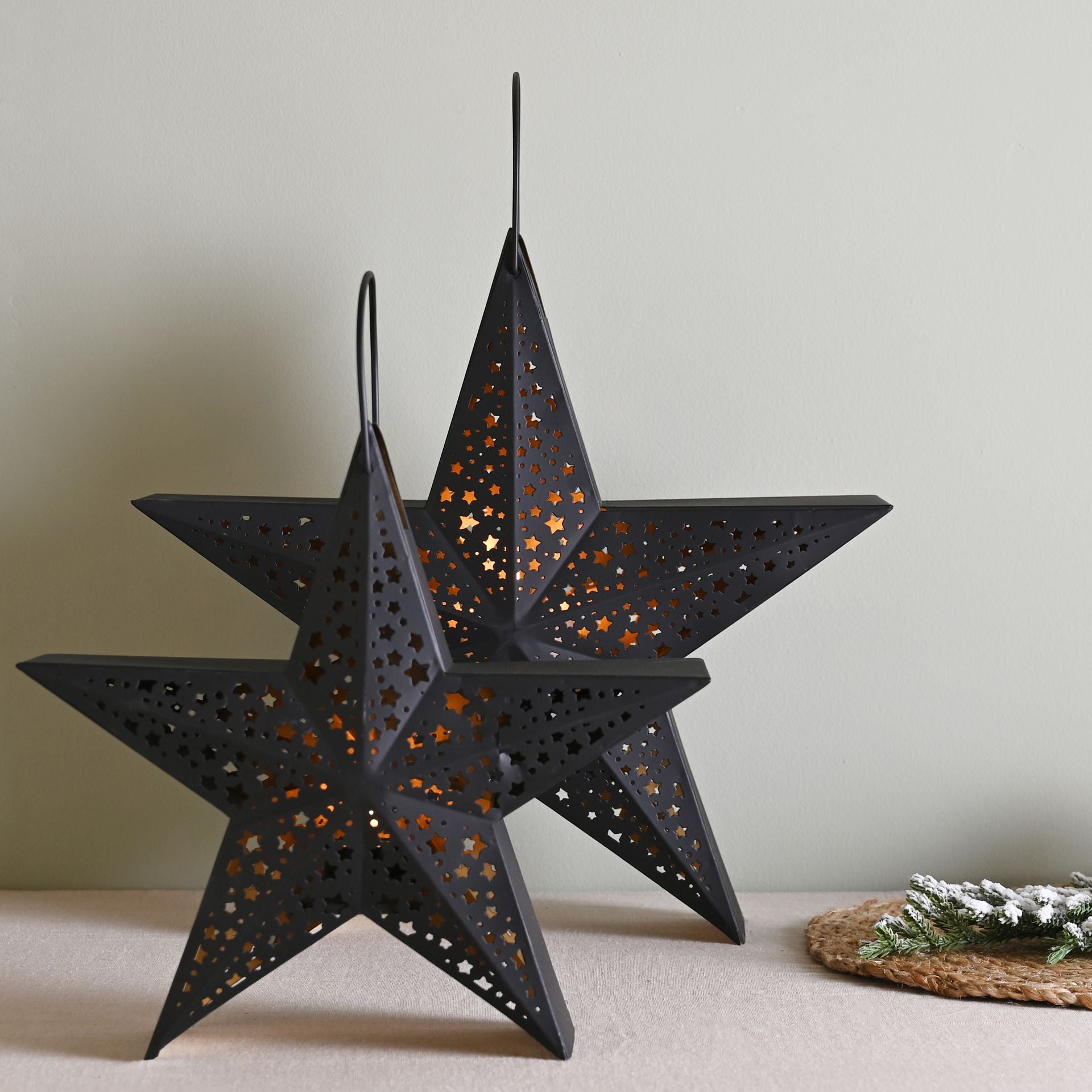 2 Black star-shaped lanterns with cut-out patterns on a white background