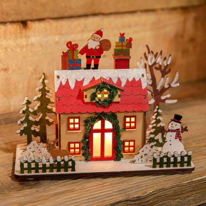 Decorative Christmas scene with a house, Santa Claus, and snowman on a wooden surface.