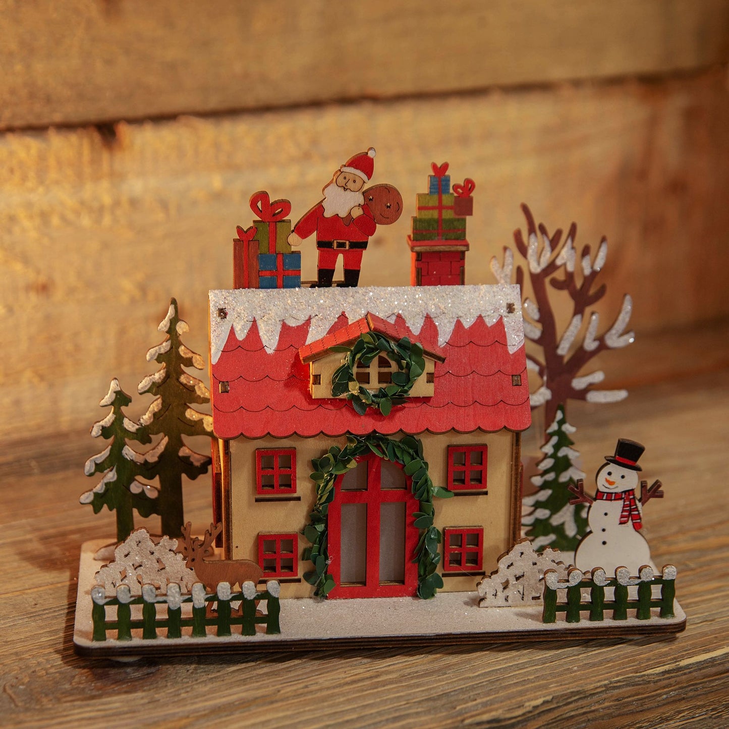 Christmas-themed wooden house with Santa Claus, presents, and a snowman on a wooden surface.