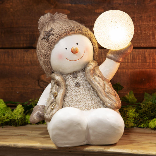 Decorative snowman figurine holding a light bulb against a wooden background