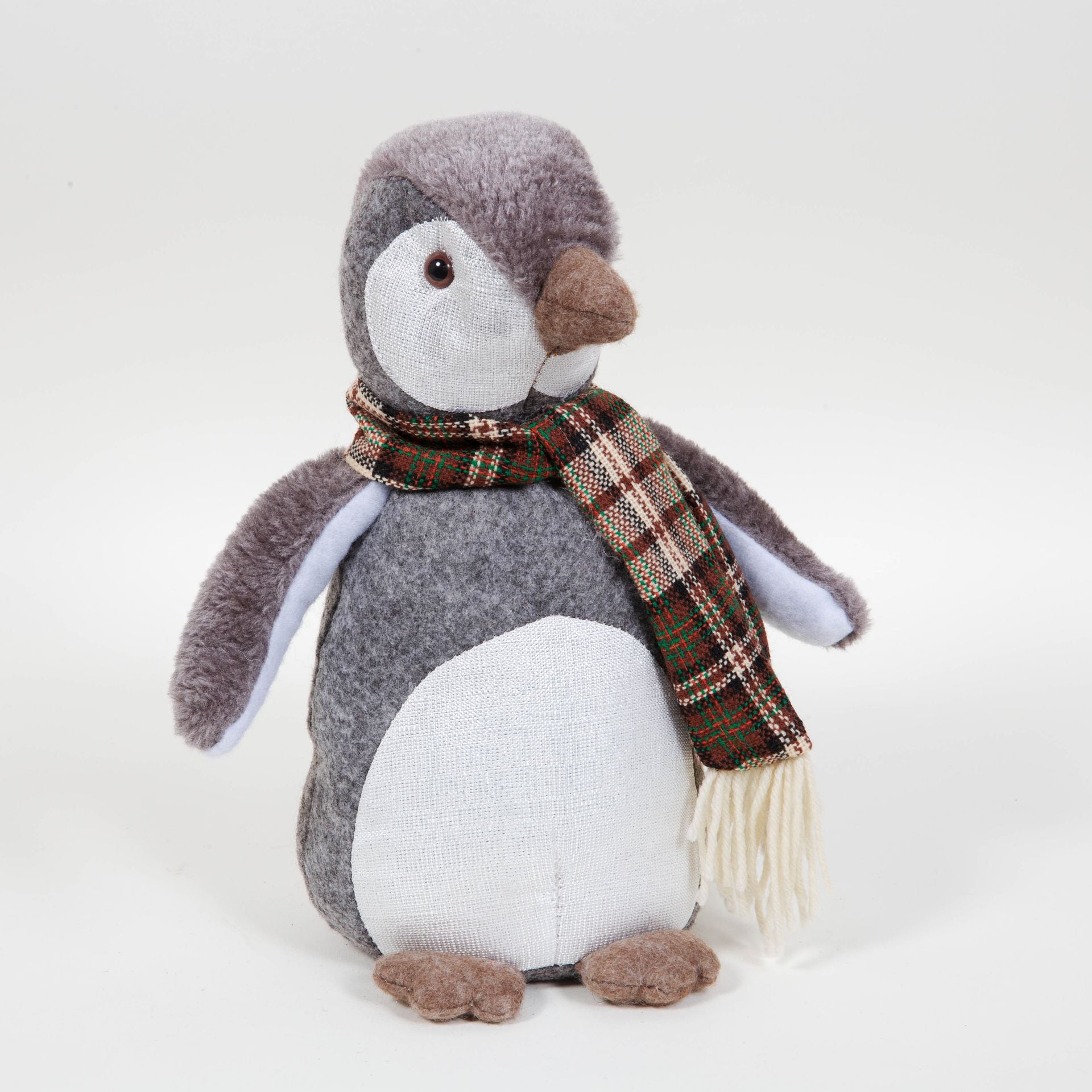 Stuffed penguin toy wearing a plaid scarf on a white background