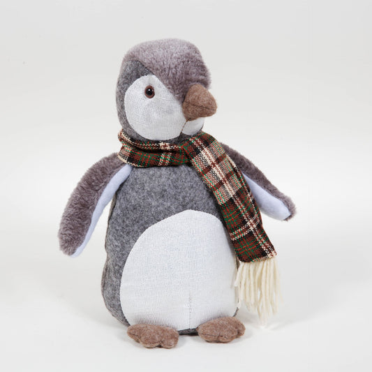 Stuffed penguin toy wearing a plaid scarf on a white background