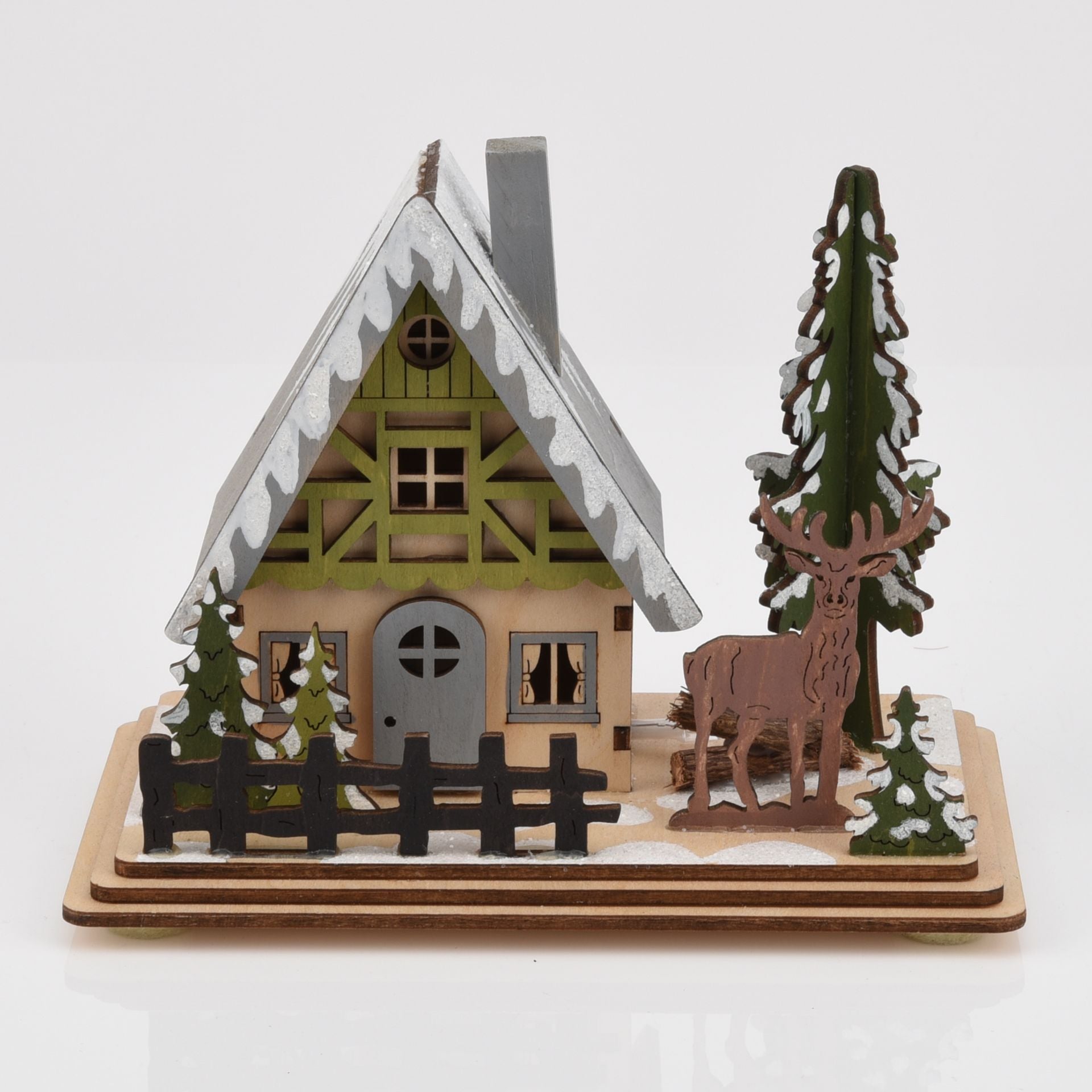 Wooden model of a cabin with a deer and trees on a white background