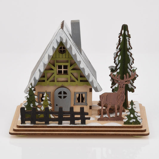 Wooden model of a cabin with a deer and trees on a white background